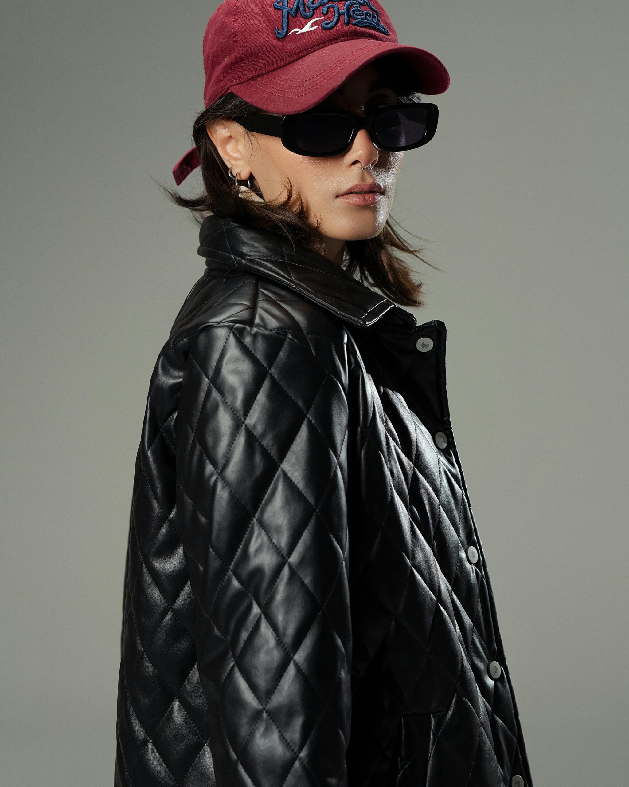 Fashionable woman in a quilted jacket, sunglasses, and cap, exuding urban style.